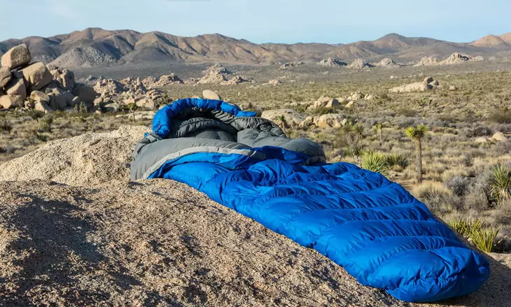 A sleeping bag on the ground and the mountains is the background