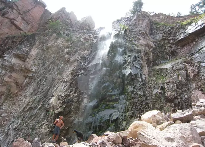 A man and a dog under the reavis falls in arizona