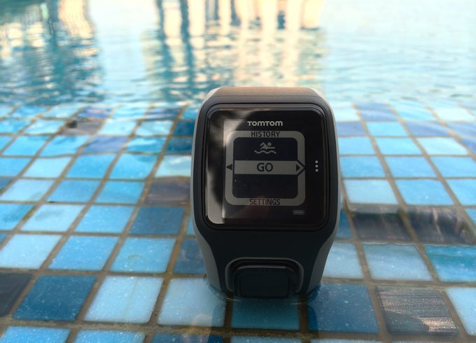 A black TomTom swimming tracker by the pool