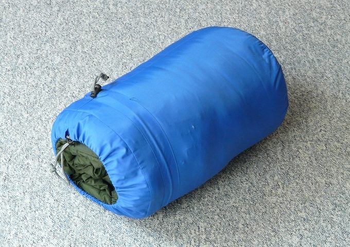 Tightly packed blue synthetic sleeping bag on the floor