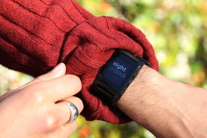 Pebble GPS tracker worn by a person on their left hand