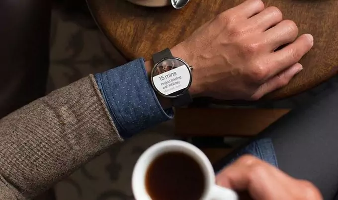 A man wearing his smartwatch while drinking coffee