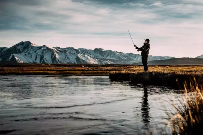 a person fishing into the lake