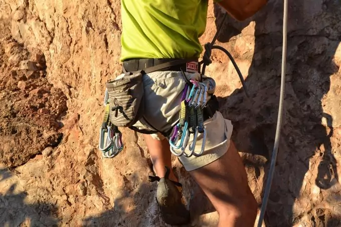 Man climbing rocks and wearing tactical belt and many accessories 