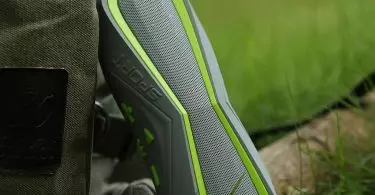 Sport silver-green wireless bluetooth speaker and a backpack on the grass