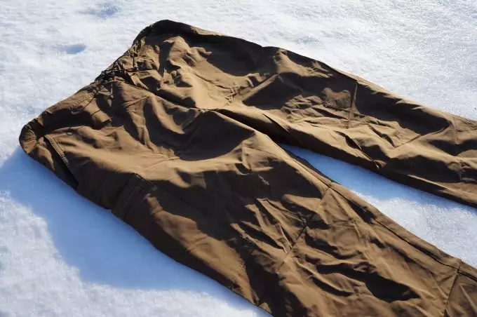 A pair of hiking pants lying on the snow
