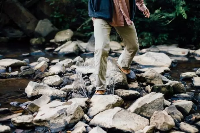 Man wearing hiking pants while crossing a river