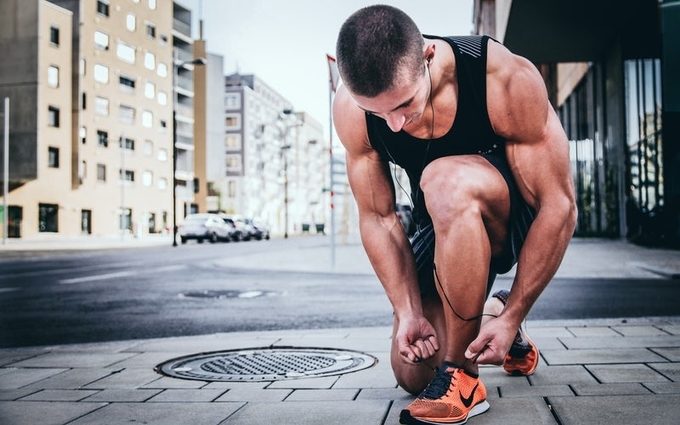 A man tying up his shoe lace and getting ready for a jog