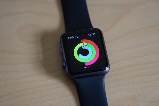 A black fitness watch on a wooden table showing activity tracking