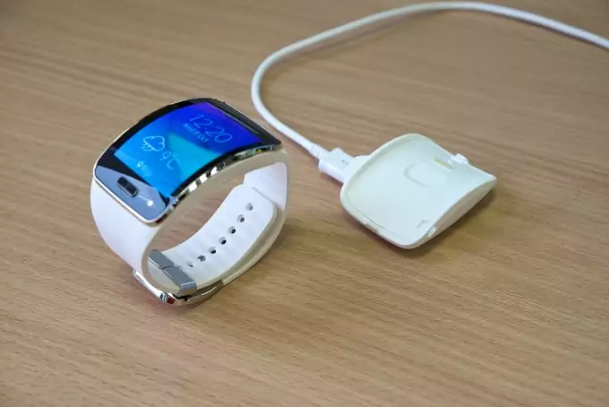 Image showing a white smartwatch and a charger on a table