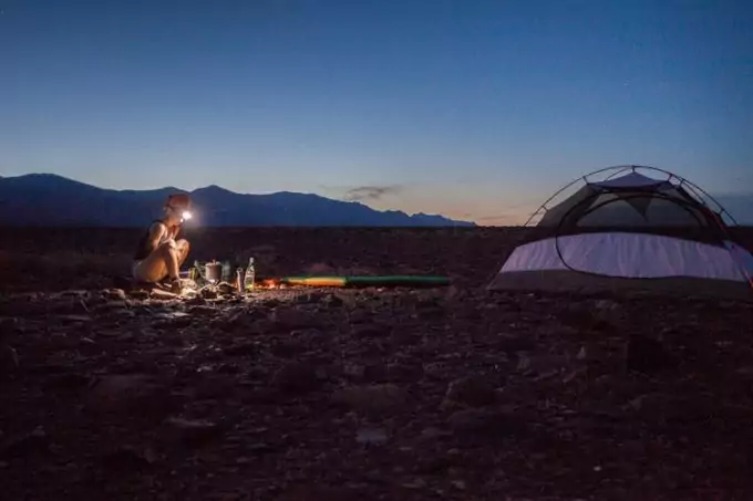 A camper outside their tent in the evening