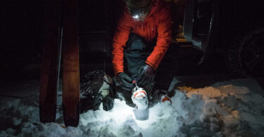 man in snow wearing headlamp